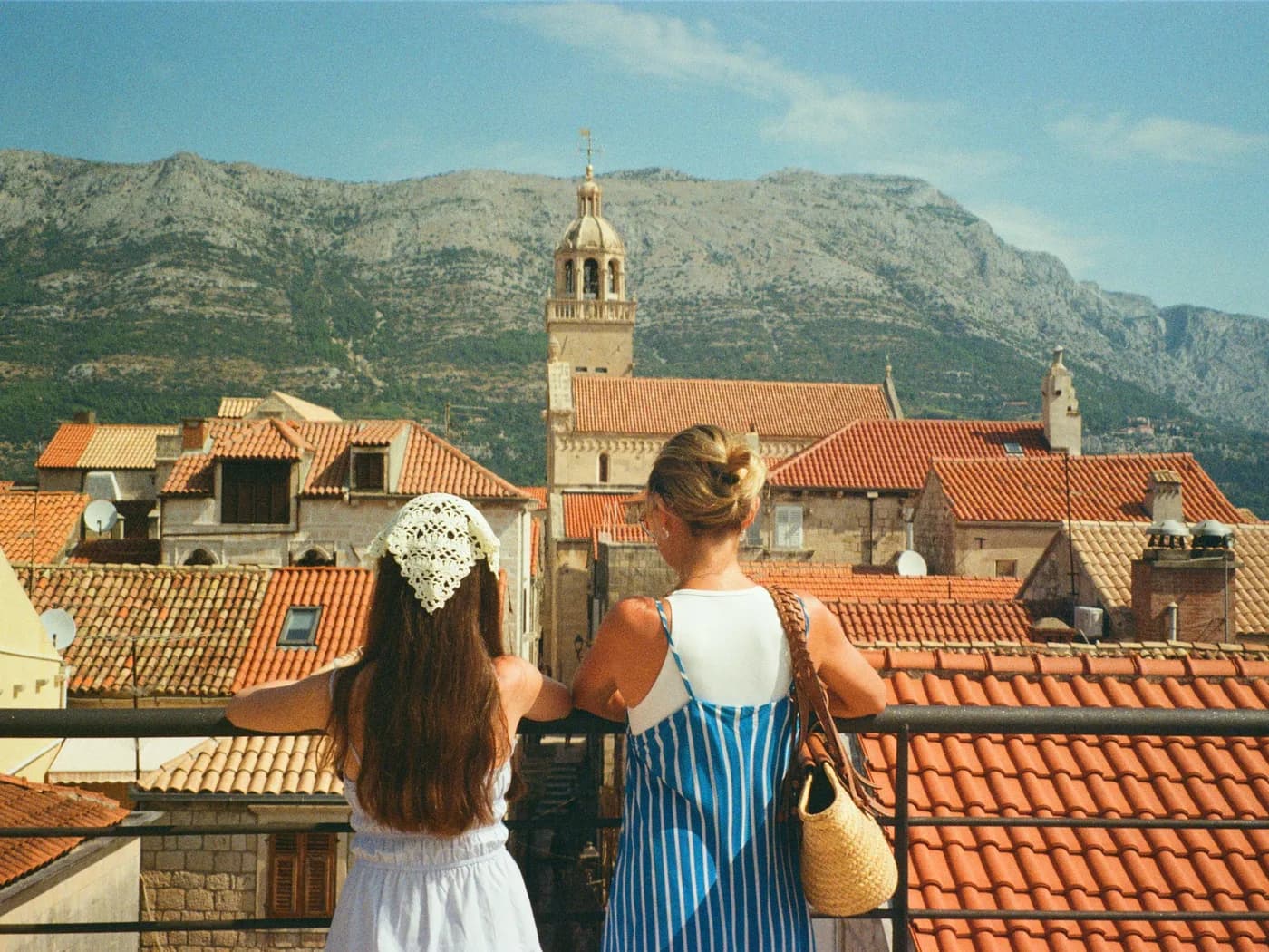 Original photo: two people seen from behind above the tiled roofs of a coastal village